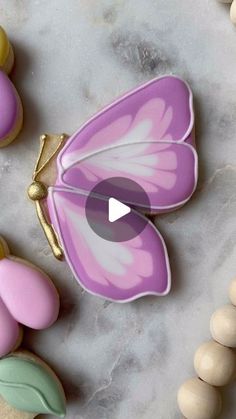 decorated cookies with pink and yellow butterflies on top of marble countertop next to beads