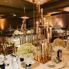 the tables are set with white flowers and gold candles for an elegant wedding reception or special event