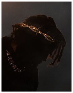 a man with dreadlocks wearing a crown of lights on his head in the dark