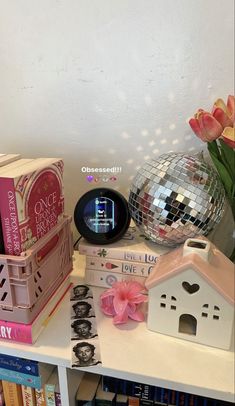 a table with books, a mirror ball and other items on it in front of a white wall