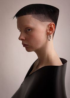 a woman with short black hair and piercings on her ears is looking off to the side