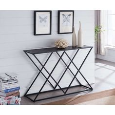 a black and white console table with two pictures on the wall in front of it