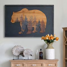 there is a bear painting on the wall next to a vase with flowers in it