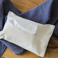 a pair of blue pants sitting on top of a wooden floor next to a white bag