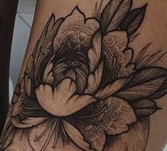 a woman's thigh with flowers and feathers tattoo on the side of her leg