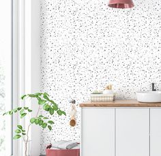 a bathroom with white walls and black dots on the wall next to a pink light fixture