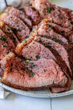 the steak is sliced and ready to be served on the plate, with parsley sprinkled on top