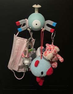 an assortment of toys hanging from hooks on a black surface with a white bag in the background