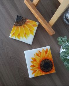 two sunflower coasters sitting on top of a wooden table