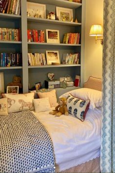 a bedroom with bookshelves, bed and stuffed animal on the pillow in front of it