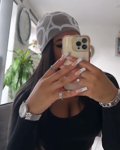 a woman taking a selfie with her cell phone in front of her face and wearing a hat