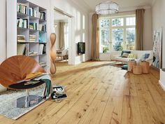 a living room filled with furniture and bookshelves on top of hard wood flooring