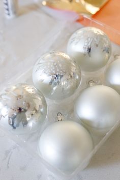 six white ornaments in a plastic container on a table