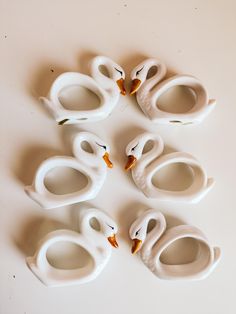 five white ceramic birds sitting on top of a table next to each other in the shape of swans