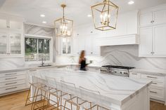 a large kitchen with marble counter tops and gold pendant lights hanging from the chandelier