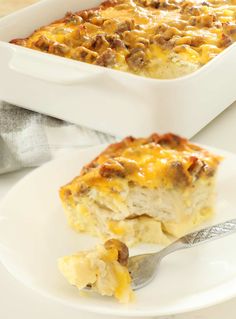 a white plate topped with a casserole covered in cheese and meats next to a fork