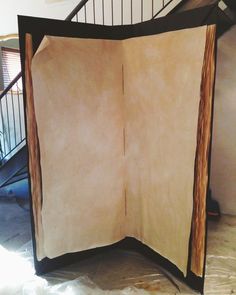 an open book sitting on top of a table next to a spiral stair case in a room