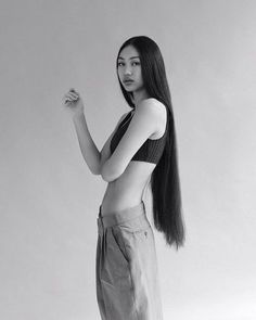 a woman with long hair standing in front of a white background