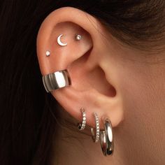 a woman with three different ear piercings on her left ear and the moon behind her ear