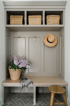 a wooden bench with baskets and flowers on it next to a wall mounted coat rack