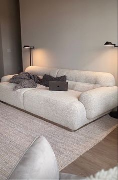 a white couch sitting on top of a hard wood floor next to a laptop computer