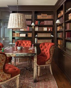 a room with many bookshelves, chairs and a table in front of it