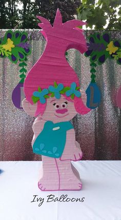 a paper cut out of a pink troll holding a blue bag on top of a table