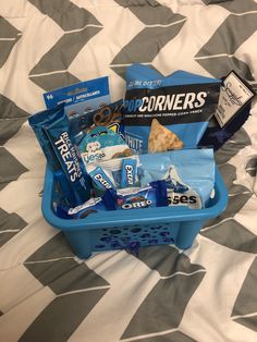 a blue basket filled with snacks on top of a bed