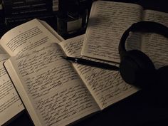 an open book with writing on it next to headphones