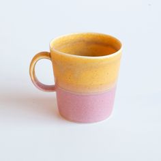 a yellow and pink cup sitting on top of a white table