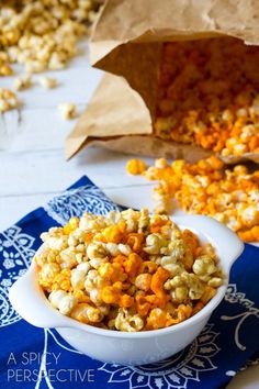 a bowl filled with popcorn sitting on top of a blue and white napkin next to a paper bag