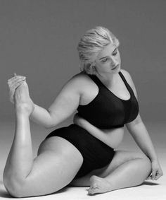 a woman in a black swimsuit sitting on the floor with her legs spread out