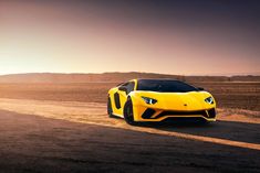 a yellow sports car driving down a dirt road in the middle of an empty field