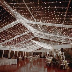 the inside of a tent with lights on it and tables set up for an event