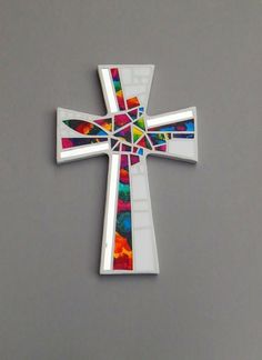 a cross made out of stained glass on a gray background with the colors of rainbow