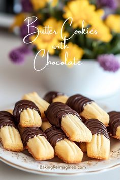 butter cookies with chocolate on a white plate next to yellow and purple flowers in a vase