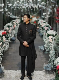 a man standing in front of a bunch of flowers