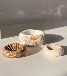 three seashells are sitting on a white surface