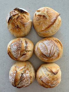 four loaves of bread sitting next to each other on top of a gray surface