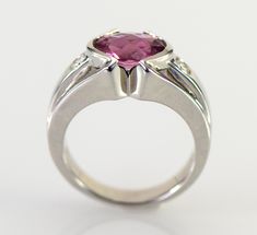 A dazzling pink Tourmaline checkerboard cut from Brazil is is accented with two flush set diamonds in this gorgeous 14k white gold ring. The natural Tourmaline is a 9 x 7 mm oval shape checkerboard cut and weighs 1.93 carats. The two diamonds are round brilliant cuts measuring 2.8mm with a total weight of .16 carats G-H color VS1-2 clarity The ring is 10.5 mm wide (3/8 inch) at the stone tapering down to 3.5 mm The height of the ring is 6 mm Ring weighs 7.31 grams Size 6 3/4 All items from Stowe Pink Sapphire Ring In Platinum For Anniversary, Pink Sapphire Platinum Ring For Anniversary, Modern Tourmaline Wedding Rings, Modern Round Cut Ruby Ring For Wedding, Modern Round Cut Ruby Wedding Ring, Pink Platinum Ruby Ring For Wedding, Modern Pink Diamond Rings, Modern Pink Diamond Jewelry, Fine Jewelry Ruby Ring Anniversary Tension Setting