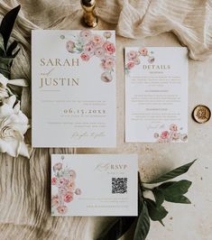 the wedding stationery is laid out with flowers and greenery