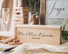 a couple's wedding guest book and wooden blocks on a table with wine glasses