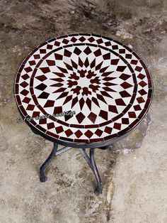 a small table with a circular design on it's top sitting on a marble floor