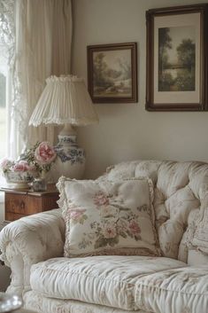 a white couch sitting in front of a window next to two pictures on the wall