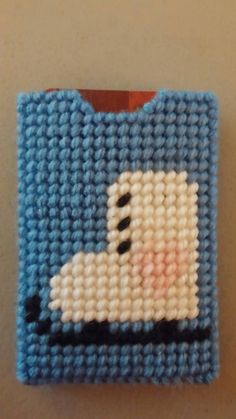 this is a needlepoint picture of a blue and white square with a cartoon character on it