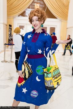 a woman in a blue dress with stars and moon on it holding a handbag