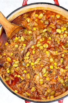 a pot filled with meat and vegetables next to a wooden spoon