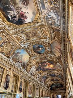 an ornate ceiling with paintings on it in a room that is painted gold and white