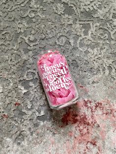 a can of pink candy sitting on the ground