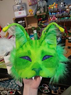 a person holding up a green cat mask